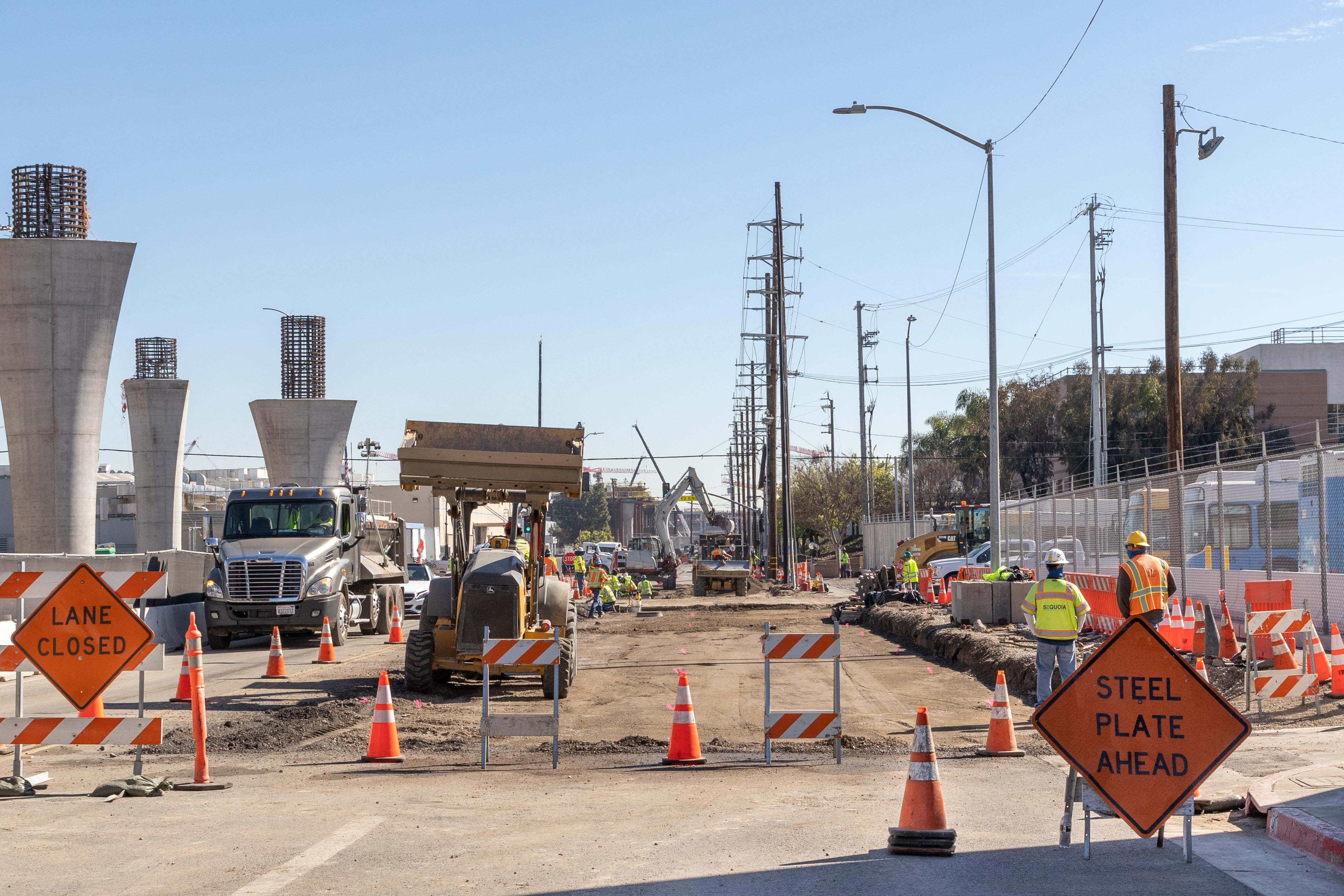Outside the system's future Maintenance and Storage Facility, crews work to expand the roadway to ease traffic impacts related to the Automated People Mover train guideway construction.