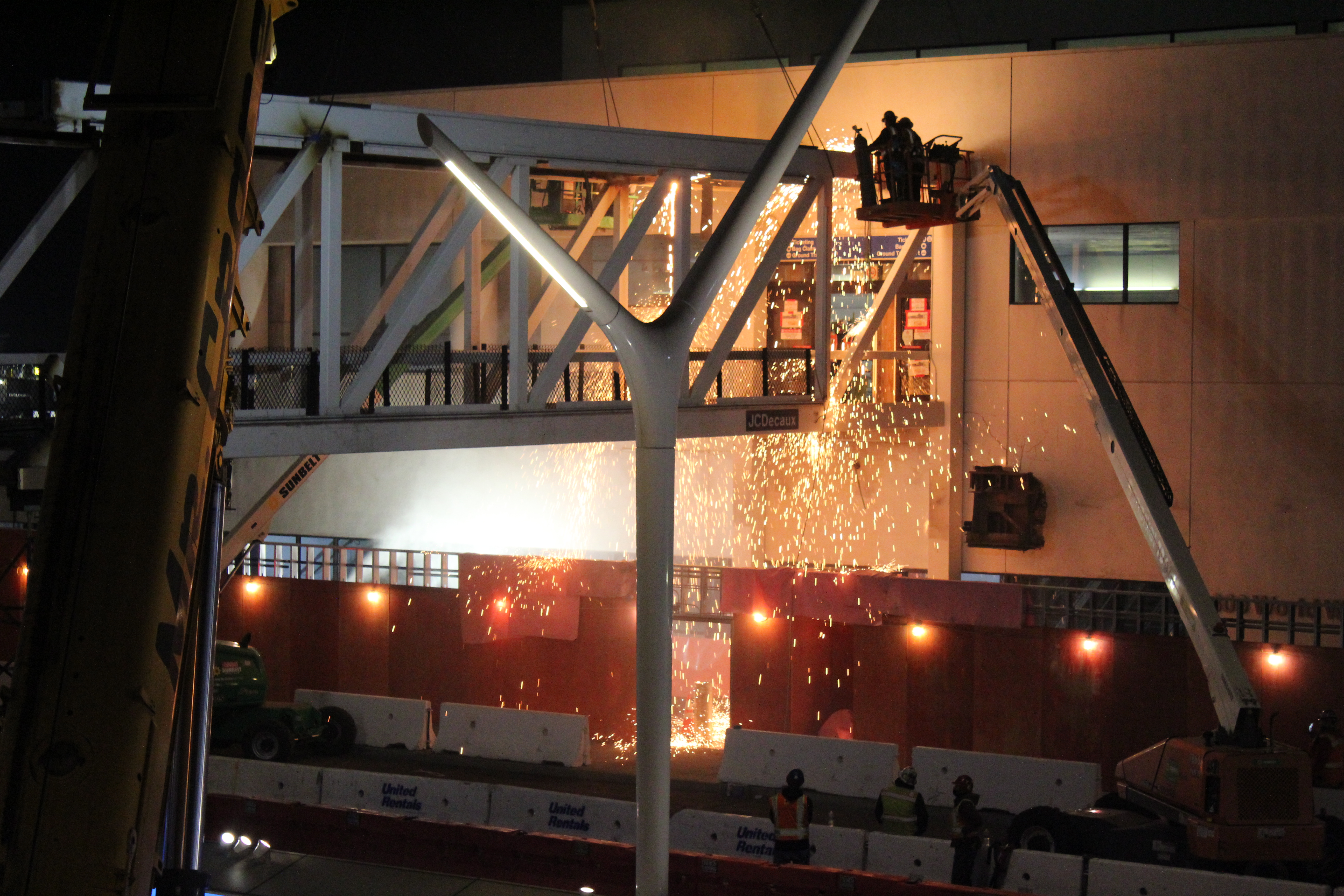 Workers use blow torches to break apart the pedestrian bridge connecting Terminal 3 to Parking Structure 3