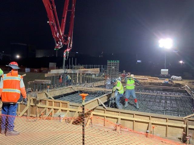 Workers pouring concrete during the early morning hours (r).